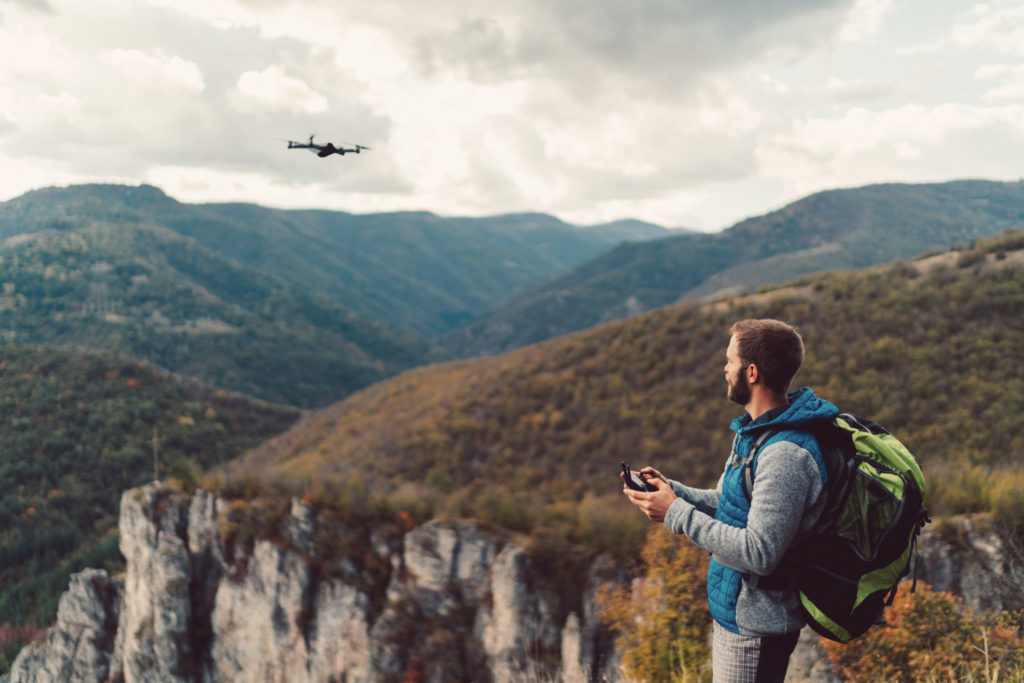 Man flies a drone over some wooded mountains