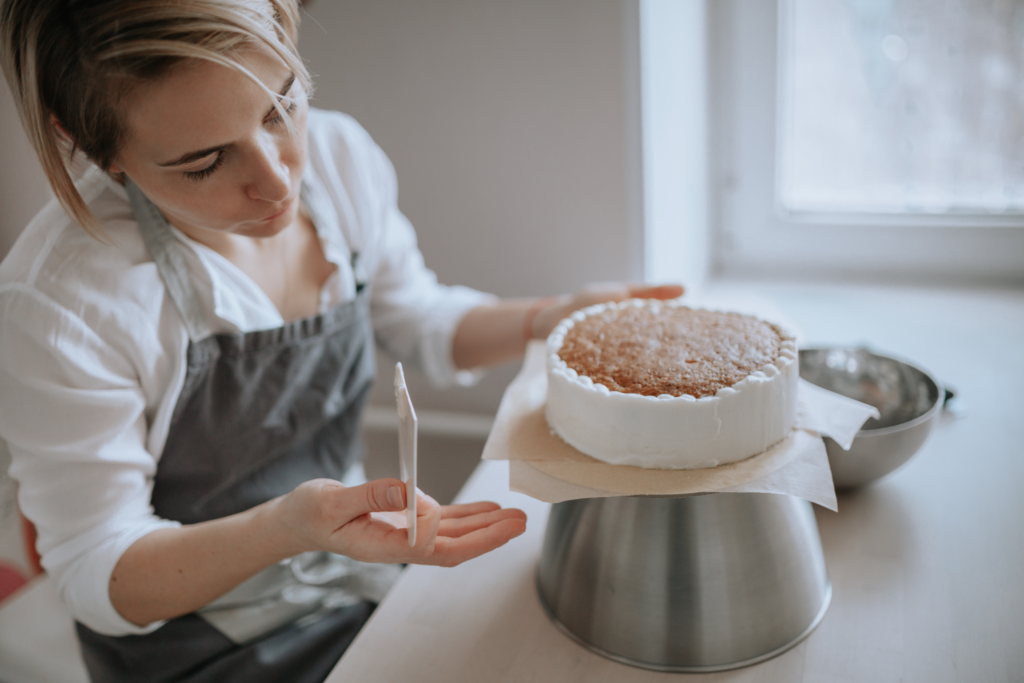 A woman decorates a cake at home. 