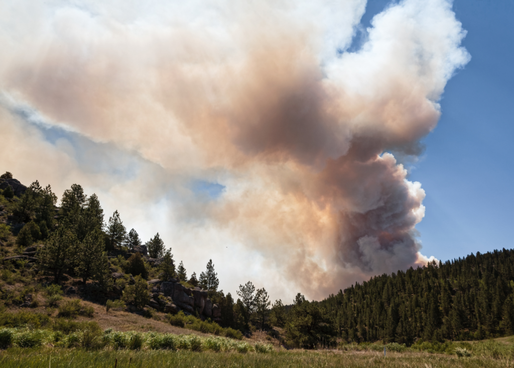 smoke from a wildfire billows over mountains in Colorado