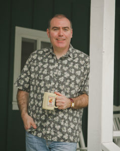 Andrew Hetzel holds a coffee mug on a porch