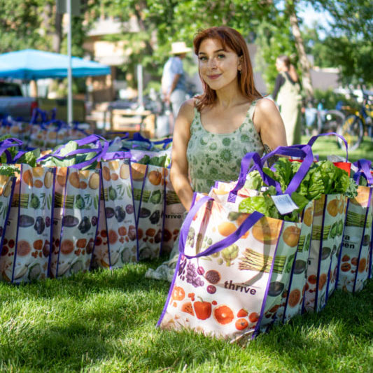 A woman smiles sitting next to bags of food