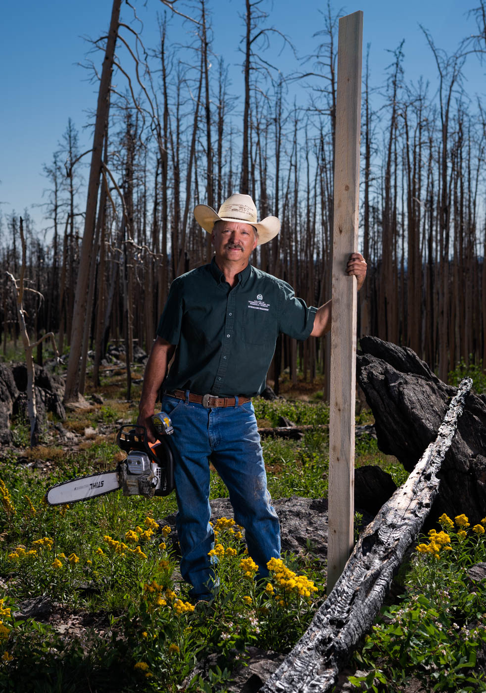 Wade Ingle holds a board standing on his property near Stove Prairie