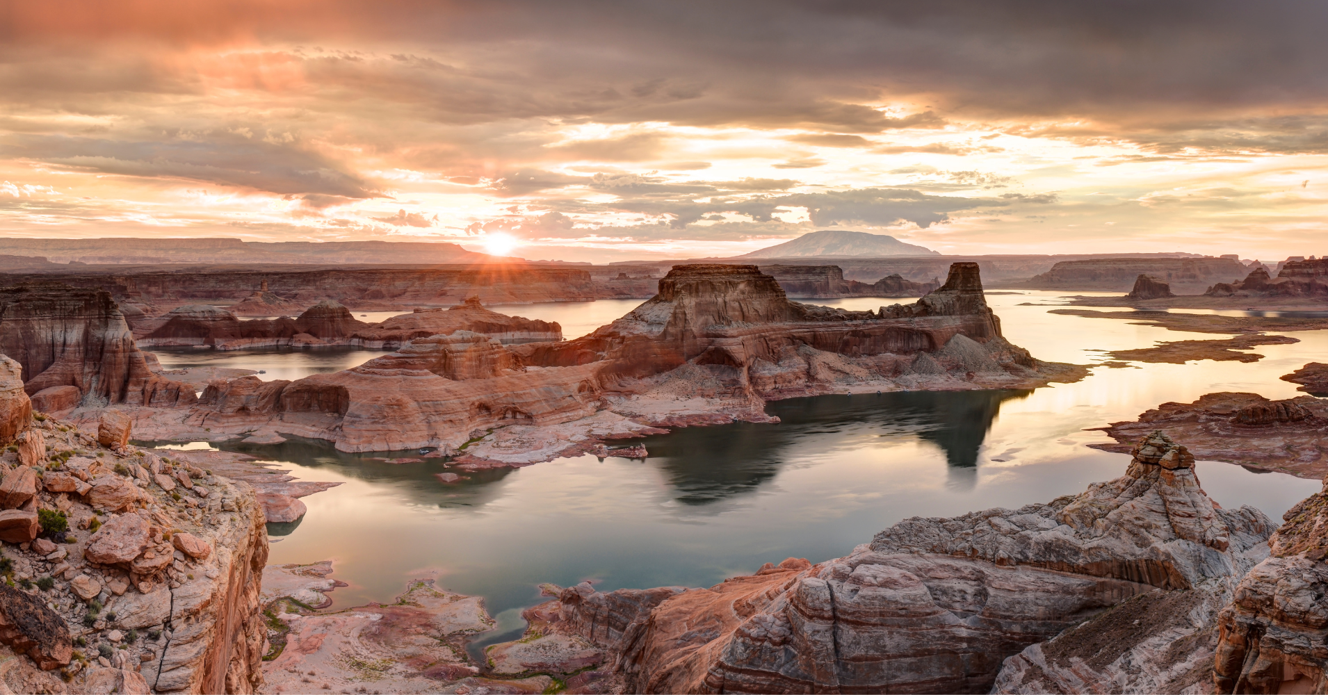 The sun sets over Lake Powell, with clear "bathtub" lines indicating low water levels