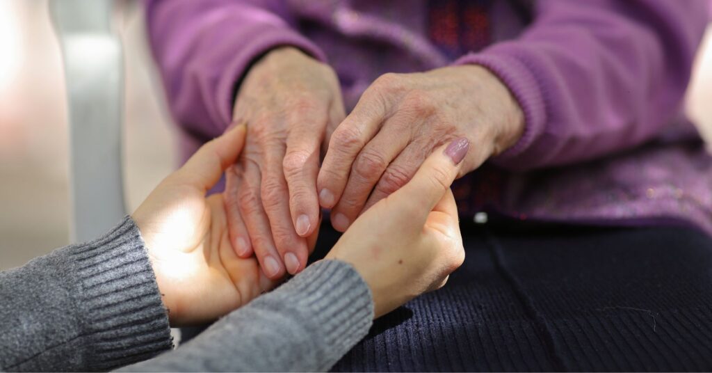 A young person holds hands with an older person