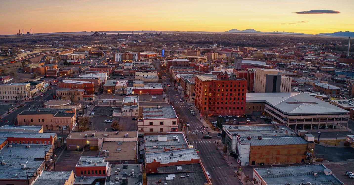 An aerial photo of downtown Pueblo, Colorado at sunset, with distant mountains in the background