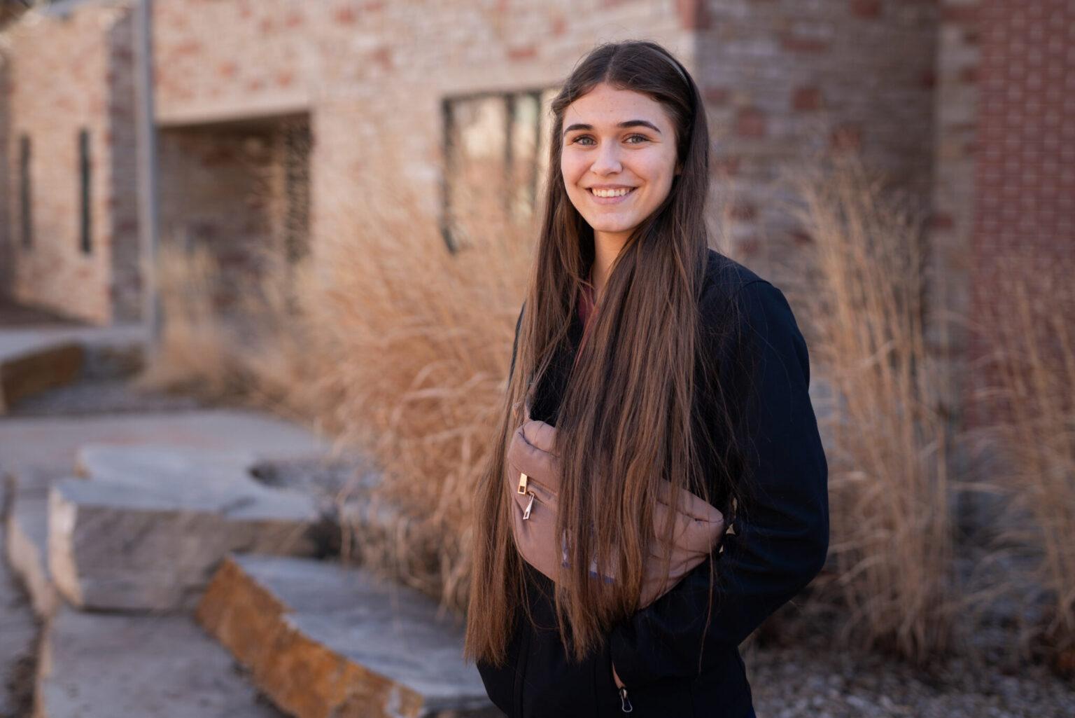 Kasey Perry stands for a portrait on campus with bricks and grass behind her